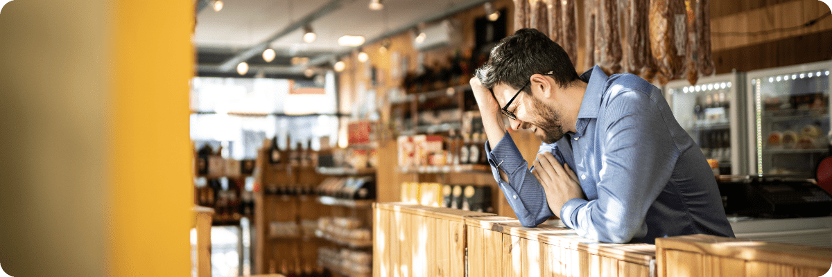 A small business owner in a retail shop looking stressed, highlighting the challenges of managing small businesses effectively.