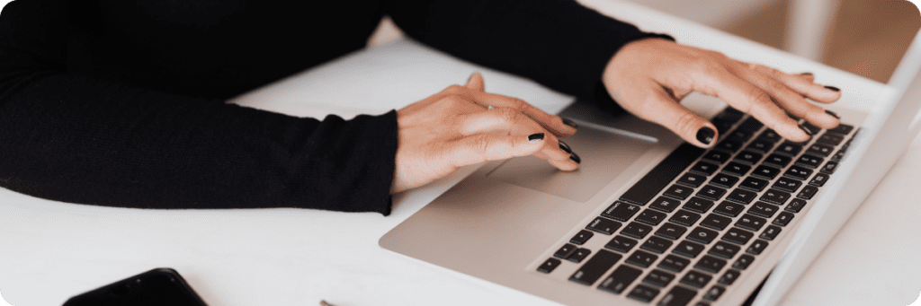 Small Business Owner typing on keyboard whilst writing her business plan