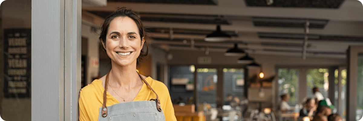 Small business owner stood in the doorway to her cafe.