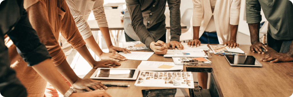 A diverse business team strategising marketing plans using both digital tools and printed materials.